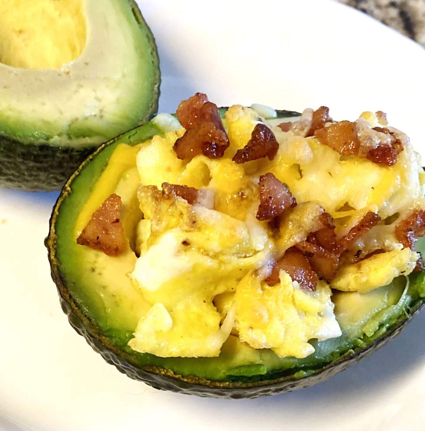 scrambled eggs bacon stuffed in avocado with cheese 