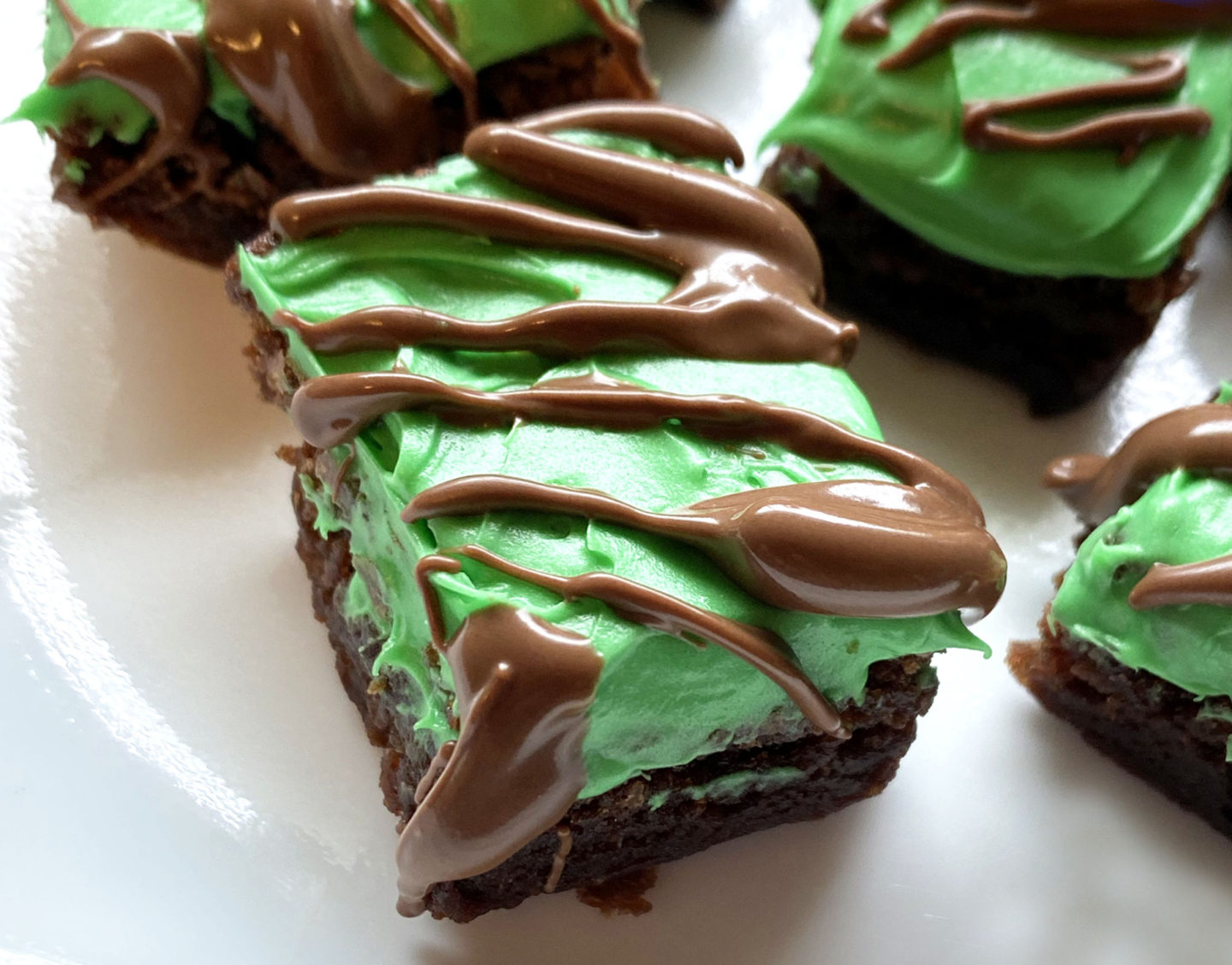 close up of creme de menthe brownies with green frosting and chocolate drizzle