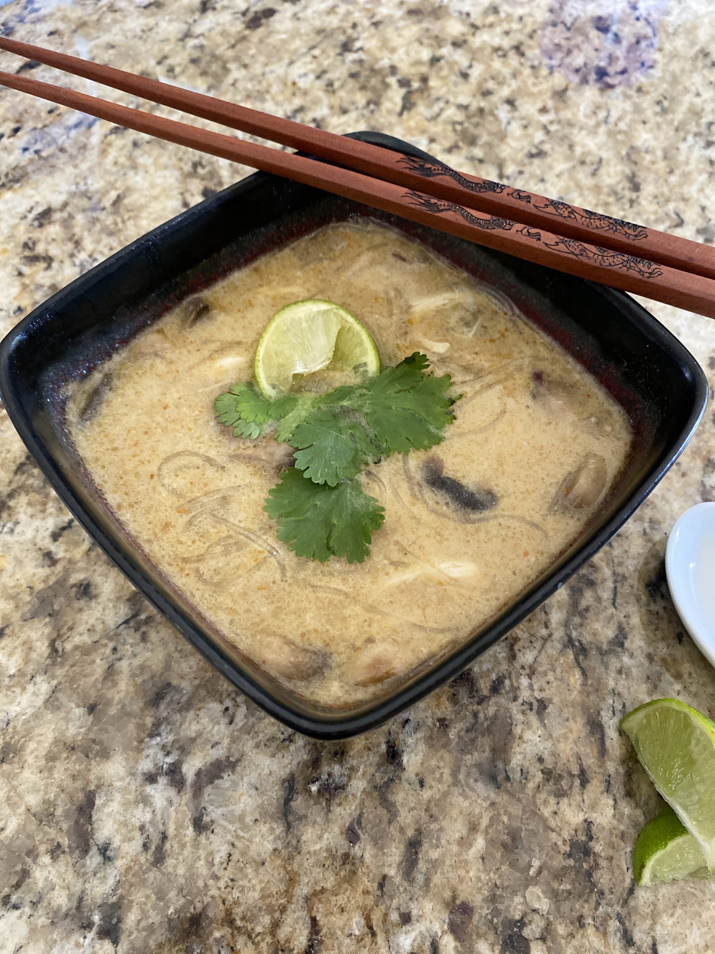 coconut lime curry soup in aa bowl with noodles and lime