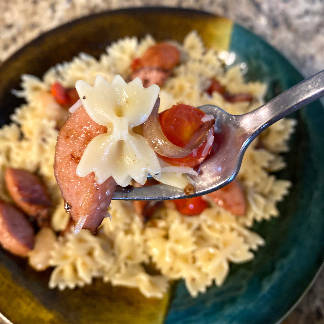 sausage shrimp and tomato pasta saute on a fork close up