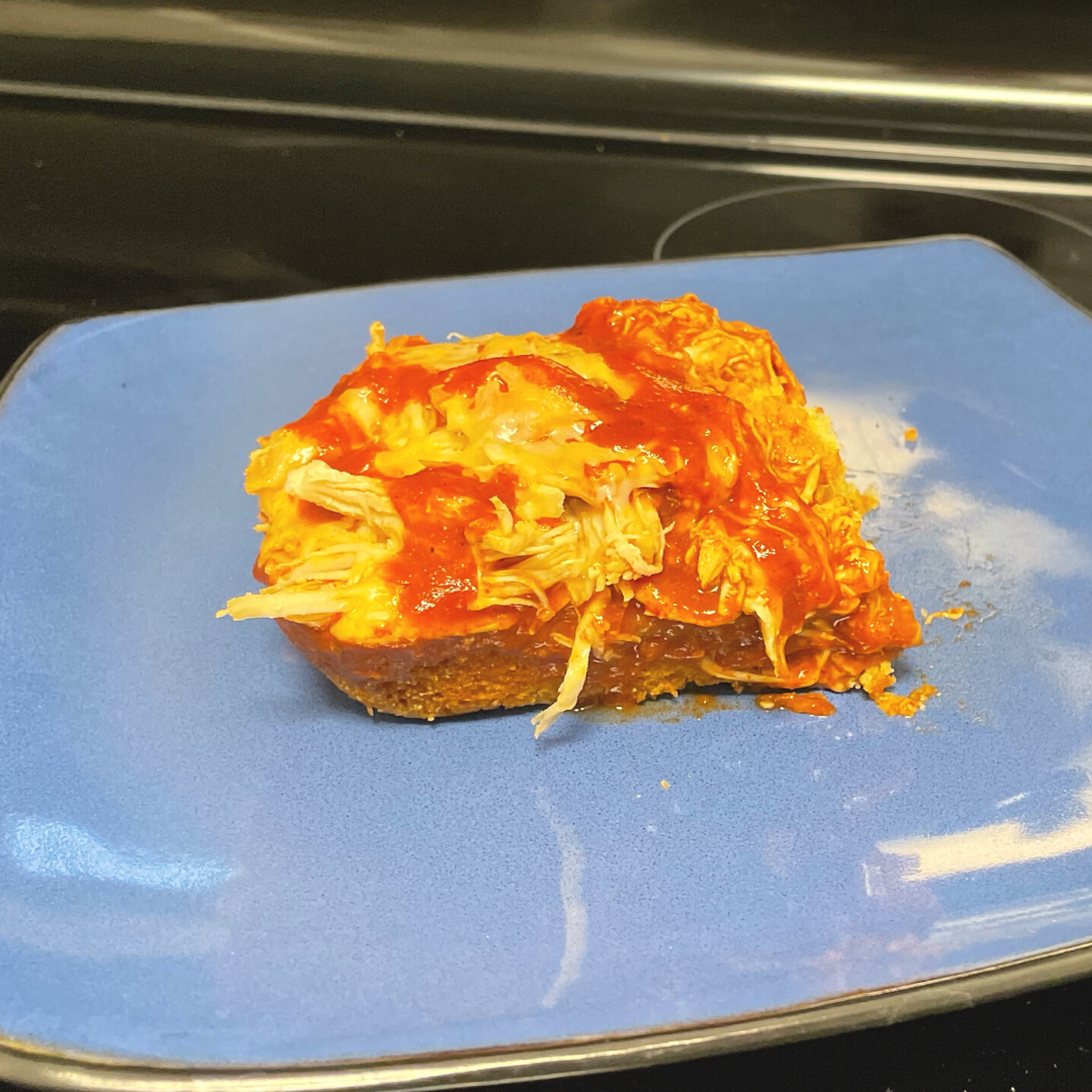 square piece of chicken enchilada on a blue plate
