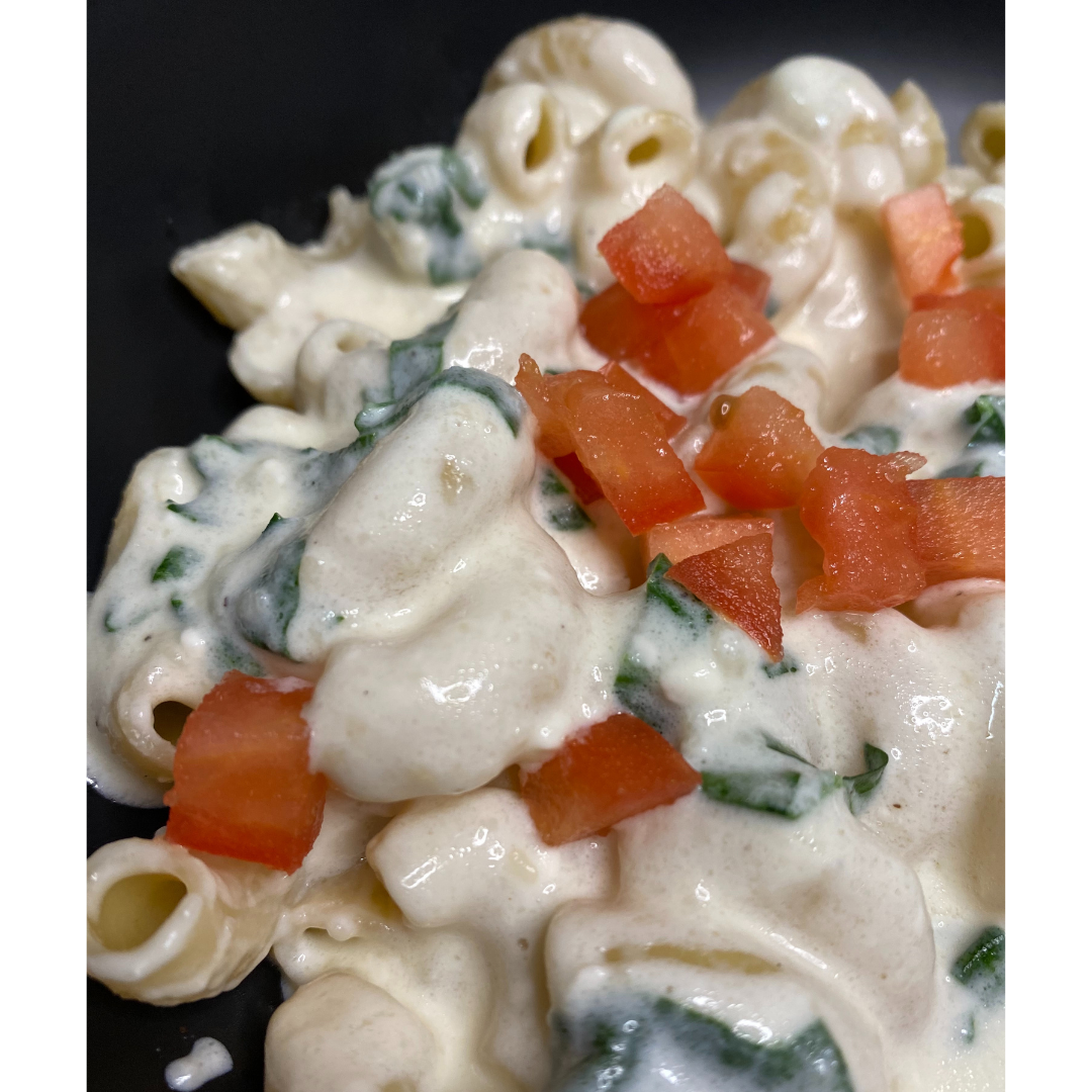 close up of white mac and cheese with spinach and tomatoes