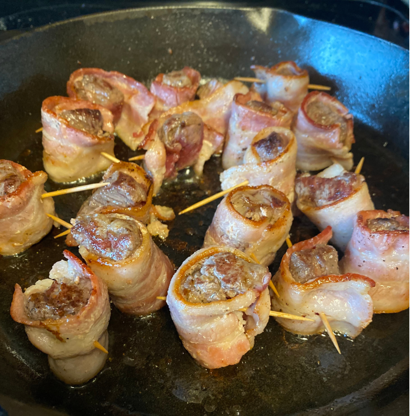 bacon wrapped steak bites cooking in skillet