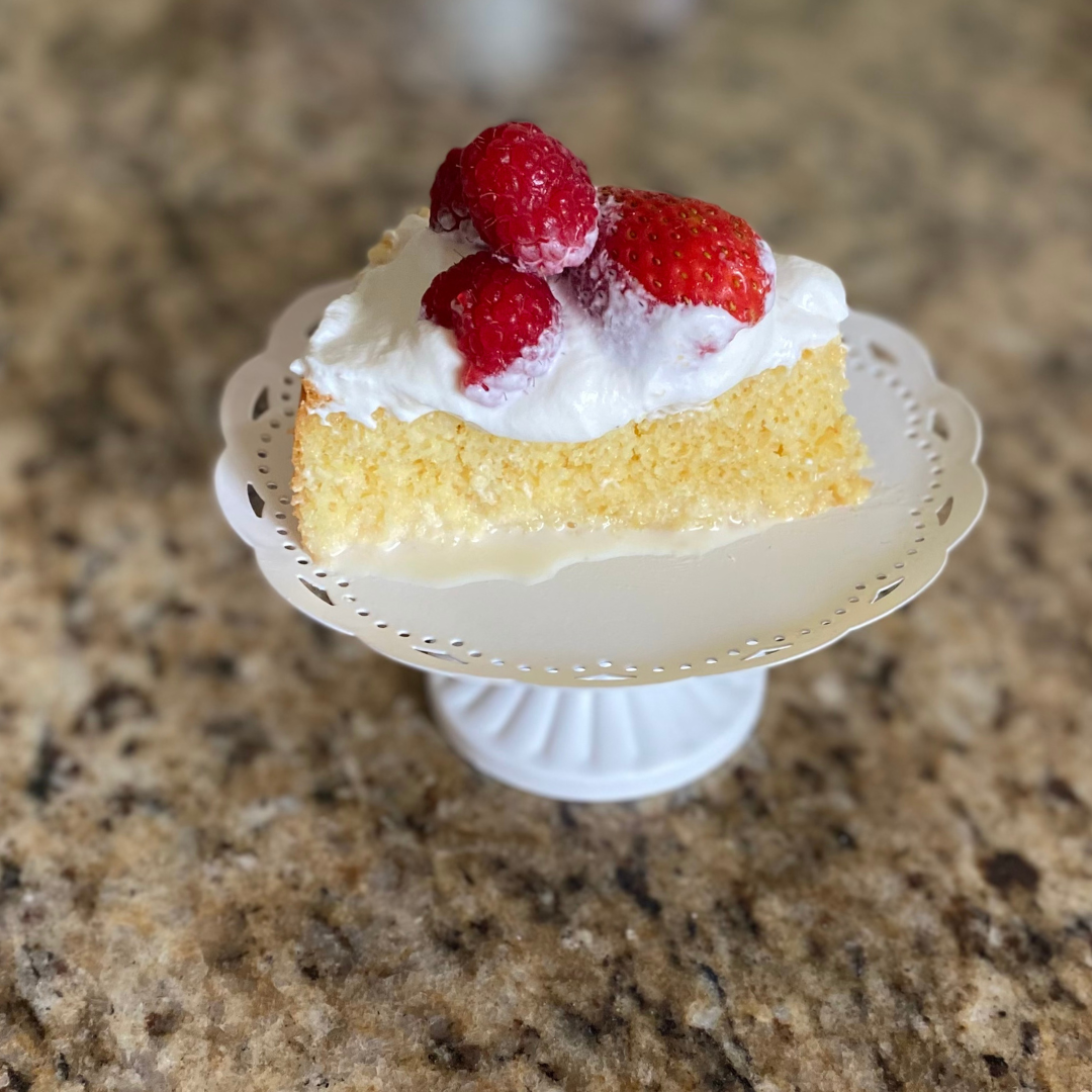slice of tres leches cake with red berries on top