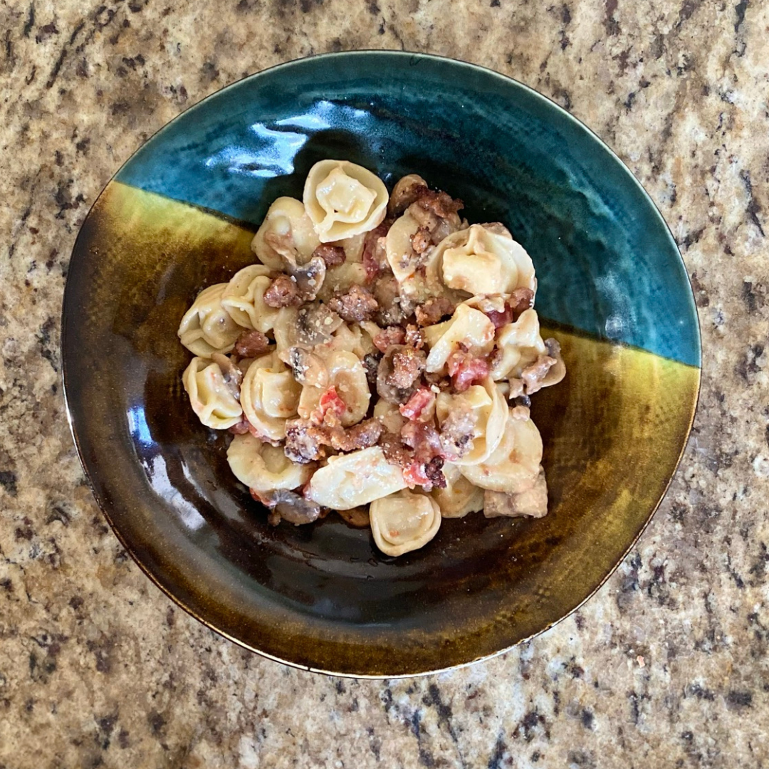 top view of sausage and tomato tortellini in bowl