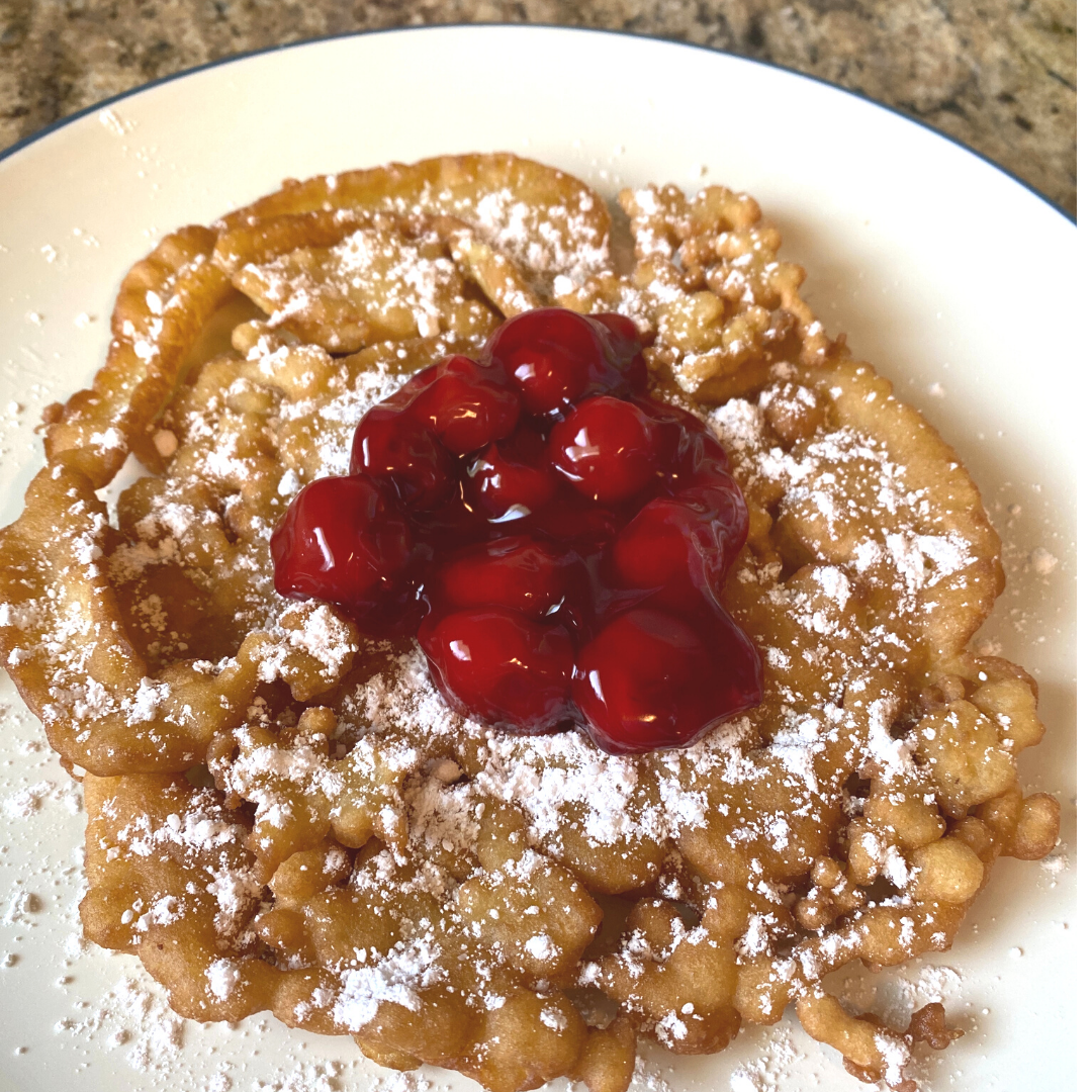 funnel cake with powdered sugar and cherry topping