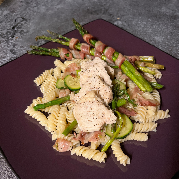 bacon wrapped asparagus side dish with chicken pasta on plate