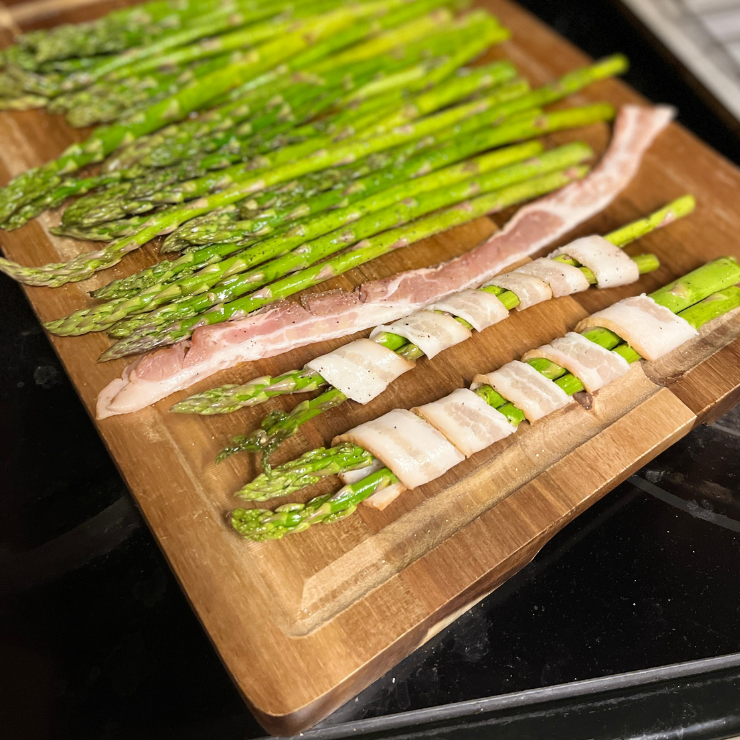 raw bacon wrapped asparagus on cutting board