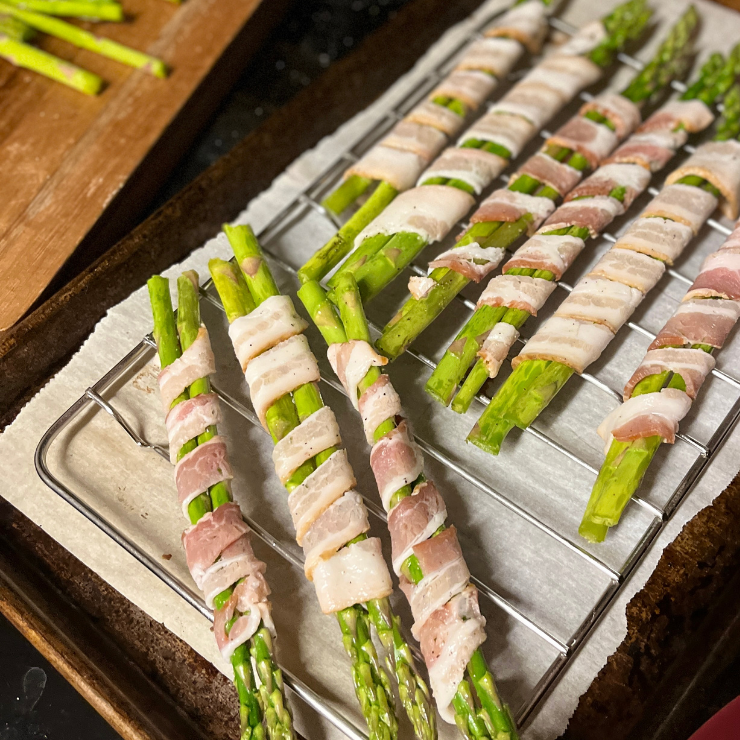raw bacon wrapped asparagus strips on baking rack