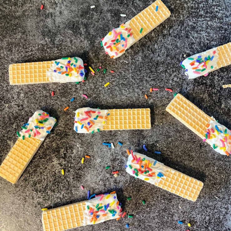 scattered chocolate dipped wafer treats with rainbow sprinkles