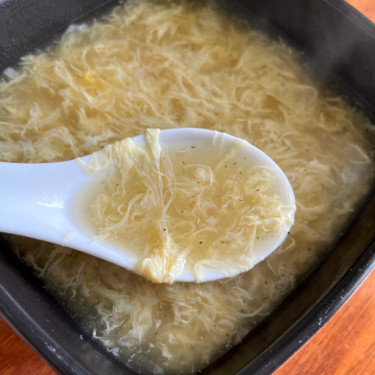 close up of egg drop soup in a spoon